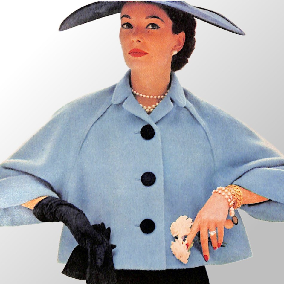 1950s woman wearing black floppy hat, long black gloves, and stylish pyramid coat.