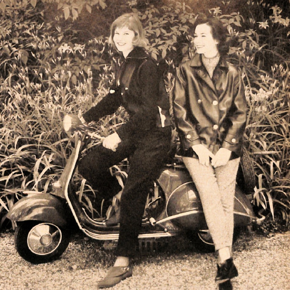 1950s women lean on Vespa dressed in casual slacks and short jackets